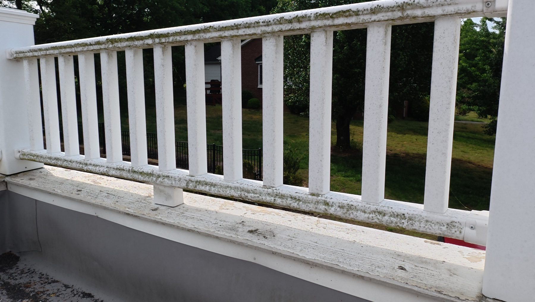 Deck railing covered in mold and mildew before cleaning
